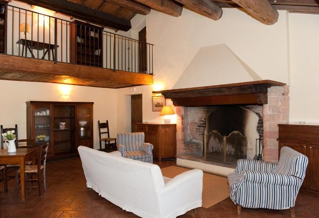 Una sala de estar acogedora con chimenea, sillones a rayas, un sofá blanco y un comedor con muebles de madera.