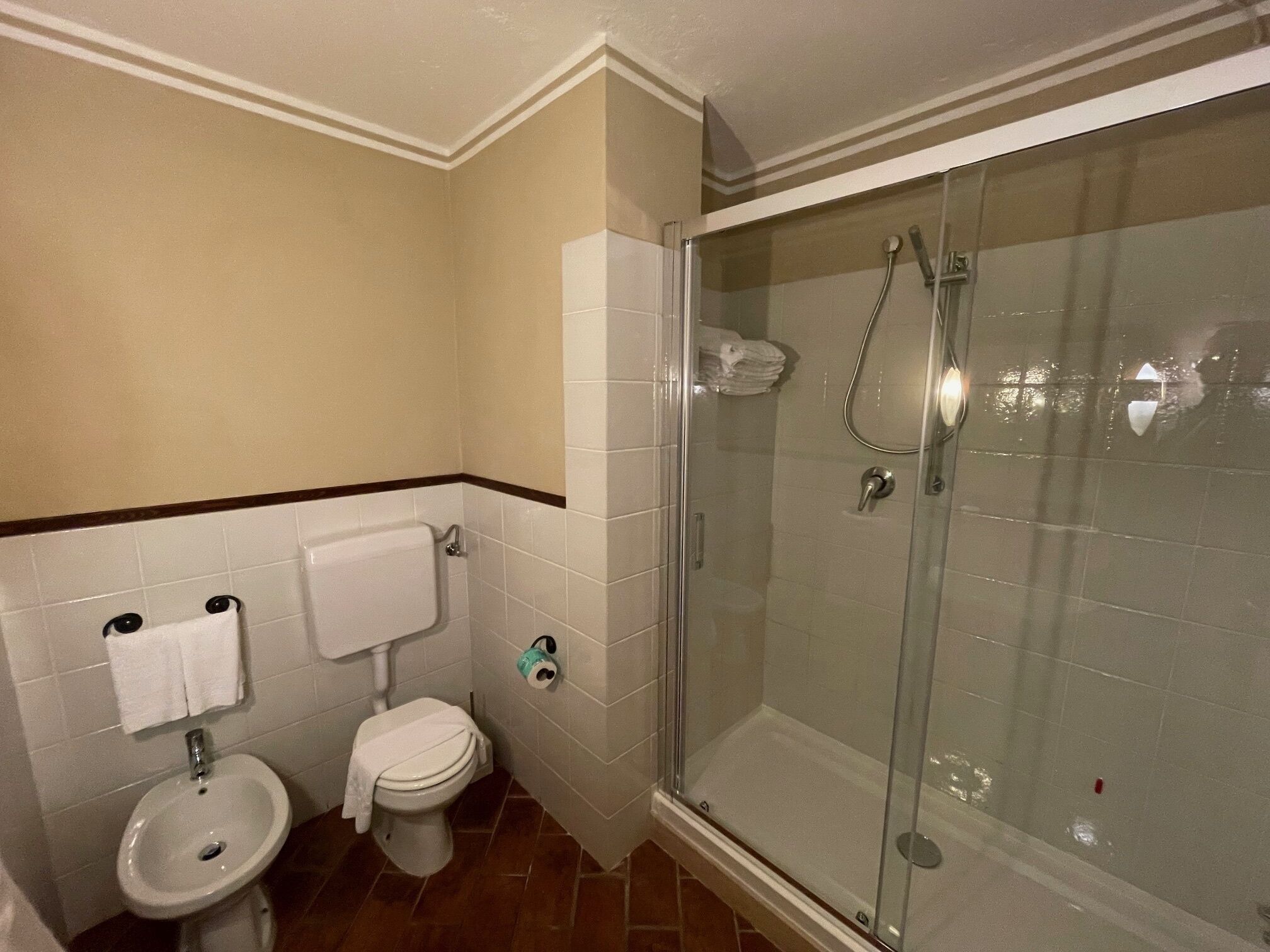 Un baño con inodoro, bidé y ducha con mampara de vidrio.