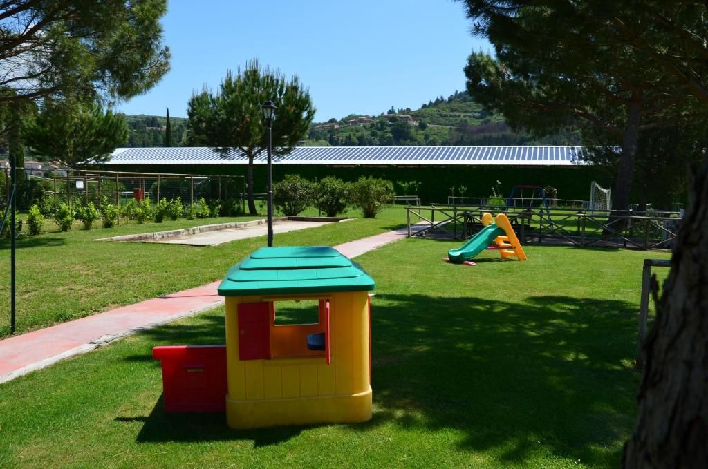 Un parque infantil con una casita de juegos, toboganes y una zona vallada.