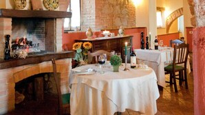 An interior with a stone archway, a fireplace, and tables set for dining. - Country House Le Case Coloniche (Deruta)