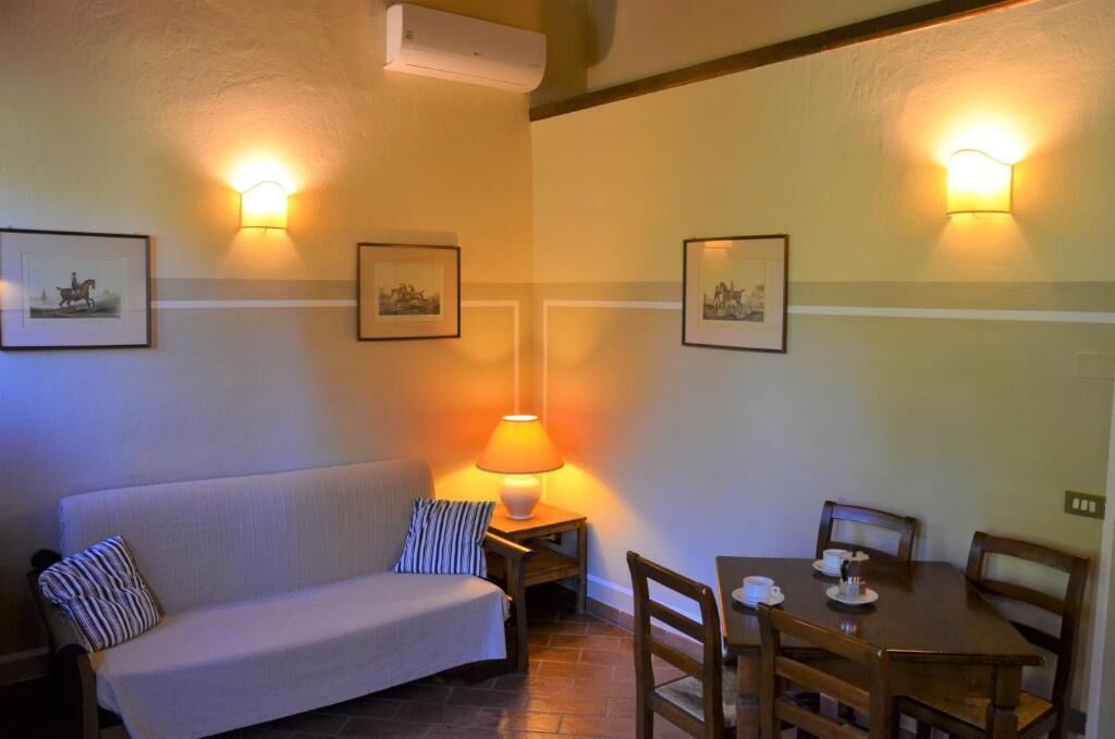 A cozy room with a sofa, a table with chairs, and wall-mounted lamps.