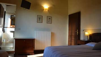 A bedroom with a bed, a dresser, a nightstand, a wall-mounted TV, and a radiator.