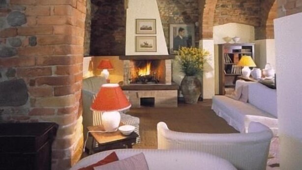 A cozy living room with a fireplace, stone arches, and comfortable seating. - Country House Le Case Coloniche (Deruta)