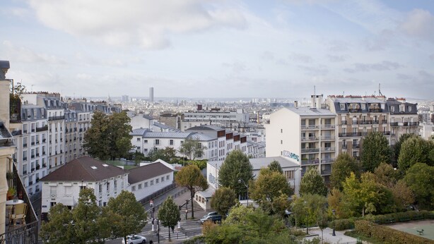 Un paisaje urbano con edificios de varios pisos, incluyendo un edificio blanco destacado con techo plano y balcones.