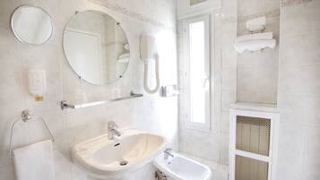 A bathroom with a sink, bidet, mirror, towel rack, and a shower area.