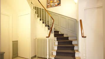 A staircase with white railings and a wooden handrail, leading to a landing with a radiator and a door.