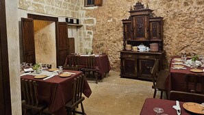 A rustic dining area with stone walls, wooden furniture, and a chandelier. - A Locanda Tù Marchese (Matino)