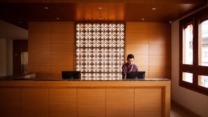 A reception desk with a patterned backdrop, a wooden counter, and a window to the right. - Hotel Osel (Thimphu)