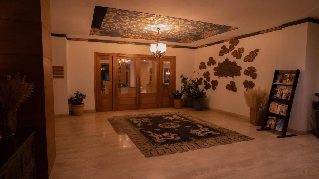 A hotel lobby with a patterned carpet, a chandelier, a wooden door, and wall-mounted decorations.