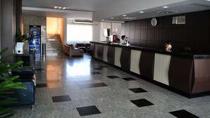 A hotel reception area with a reception desk, seating area, and a staircase leading to an upper floor. - Pinheiro Palace Hotel (Rio Branco)