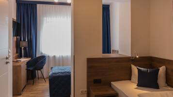 Ein Hotelzimmer mit einem Holztisch, einem Sessel, einem Bett mit Kopfteil, einem Nachttisch und einem Spiegel.