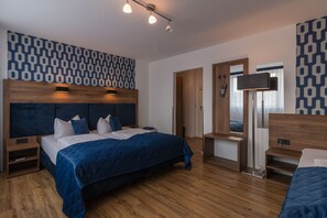 Un dormitorio moderno con una cama grande, mesitas de noche, un televisor y un papel tapiz estampado.