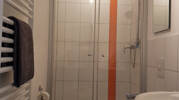 Ett badrum med en dusch som är avskärmad med glasväggar, en toalett och ett handfat.