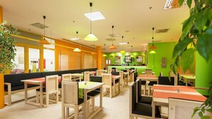 A restaurant with wooden tables and chairs, a counter, and a green wall. - Dvorak (Ceske Budejovice)