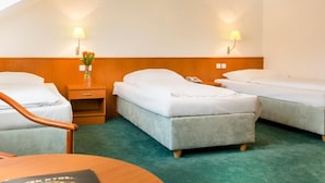 A hotel room with two beds, a wooden nightstand, a desk, and a green carpet. - Dvorak (Ceske Budejovice)