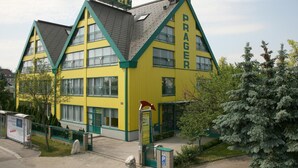 Un immeuble jaune sur lequel on peut lire l’inscription « HÔTEL PRAGER ».
