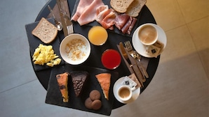 Desayuno con tostadas, huevos, tocino, queso y café sobre una mesa redonda.