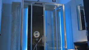 Un baño moderno con cabina de ducha de vidrio, una lámpara de techo visible y una zona de lavabo.