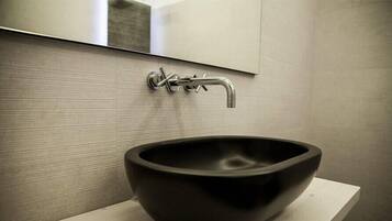 A modern bathroom with a black vessel sink, a chrome faucet, and a mirror above the sink.