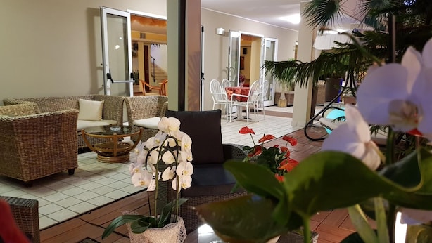 A living room with wicker furniture, a glass coffee table, and a dining area with white chairs.
