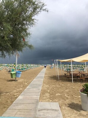 Une plage avec un sentier, des chaises de plage et des parasols.