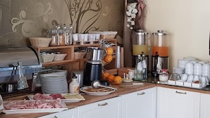 A breakfast bar with a variety of food items, a coffee machine, and a TV mounted on the wall.