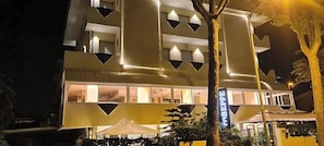 A multi-story building with illuminated windows and a sign that reads 'Hotel.' - Hotel Beppe (Rimini)
