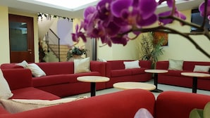 A red sofa set with two round tables, a staircase, and a potted plant.