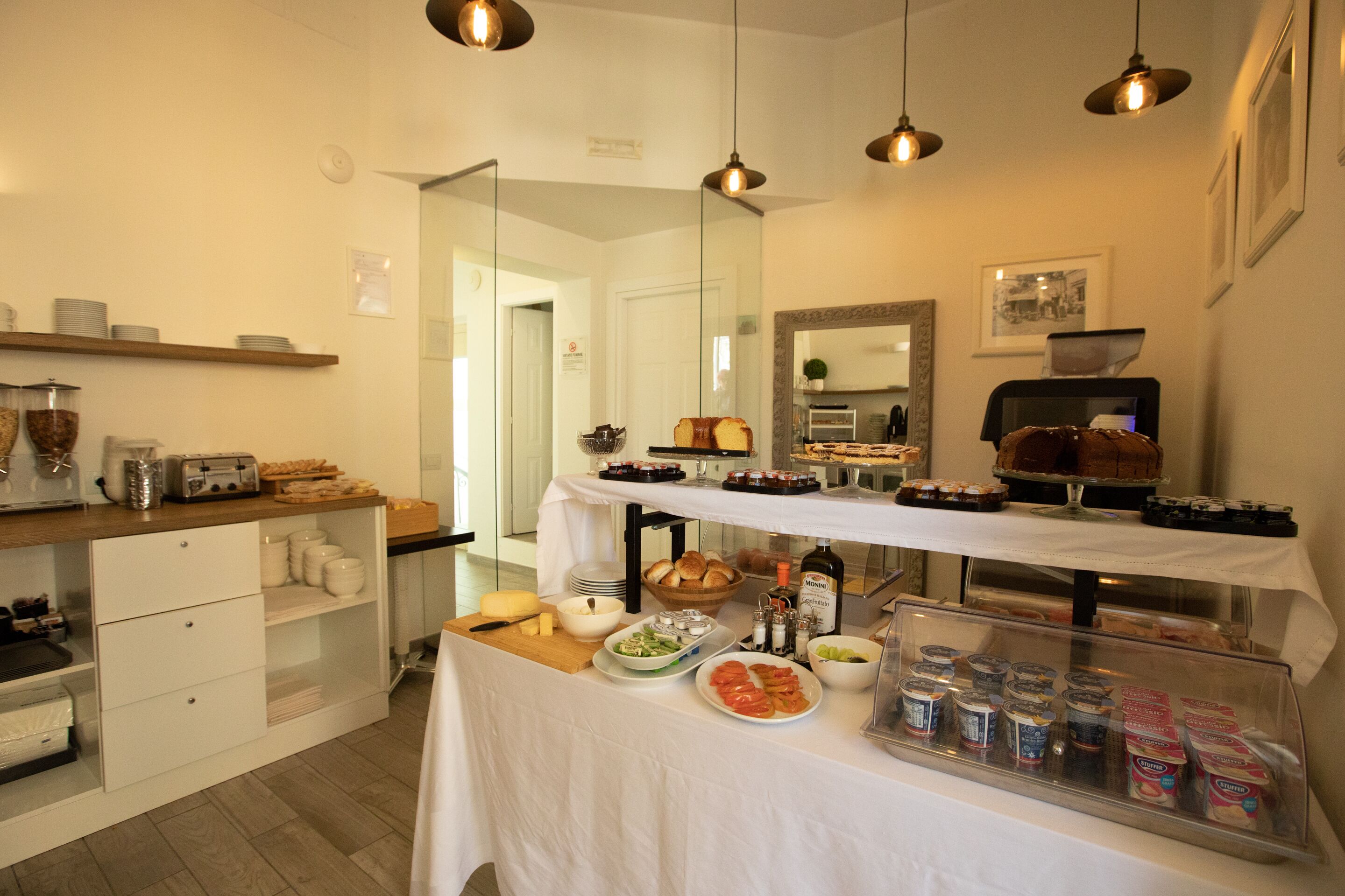 Un bufé de desayuno con diversos alimentos y bebidas, una máquina de café y un espejo en la pared.