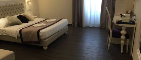 Habitación de hotel con cama, mesita de noche, silla y vistas al exterior a través de la ventana.