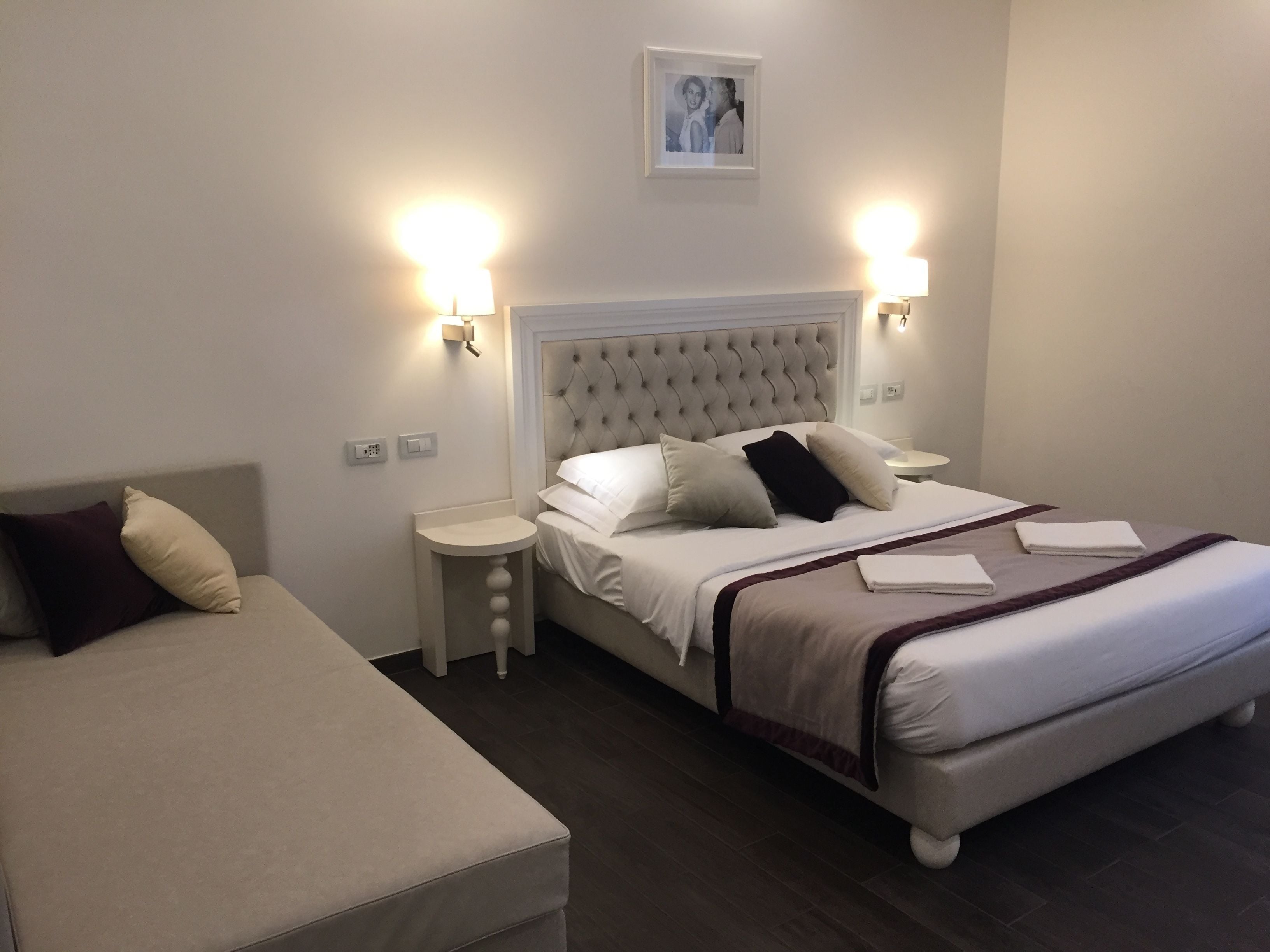 A hotel room with a large bed, two bedside tables, and a small round table.