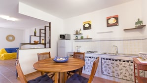 A compact kitchen with a dining area, white walls, and tiled backsplash. - Stagnone Holiday Apartment (Marsala)