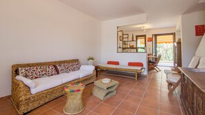 A living room with a wicker sofa, a bench, and a wooden table. - Stagnone Holiday Apartment (Marsala)