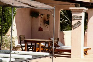A covered outdoor seating area with a table and chairs, a bench, and a sign indicating a quiet area. - Agroturismo Can Pujolet (Sant Antoni de Portmany)