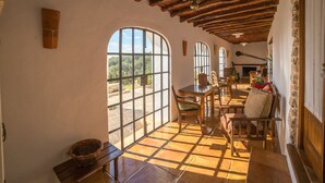 A spacious room with a high ceiling, large arched windows, and a rustic wooden ceiling. - Agroturismo Can Pujolet (Sant Antoni de Portmany)