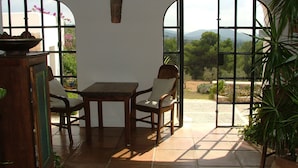 A patio with a table and chairs, a view of the outdoors, and a door with a view of the landscape. - Agroturismo Can Pujolet (Sant Antoni de Portmany)