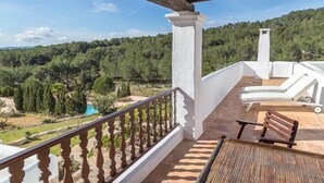 A balcony with a wooden railing, a white column, a wooden bench, and a white lounge chair. - Agroturismo Can Pujolet (Sant Antoni de Portmany)