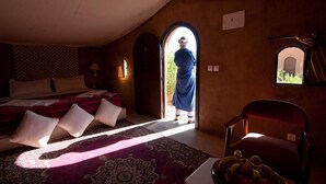 A bedroom with a bed, pillows, a chair, a table, and a window. - Hotel Bab Rimal (Foum Zguid)