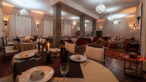 A formal dining room with tables set for service, chandeliers, and a carpeted floor. - Hotel Bab Rimal (Foum Zguid)