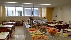 A buffet setup with various food items and a clock on the wall. - Atalaia Apart Hotel (Aracaju)