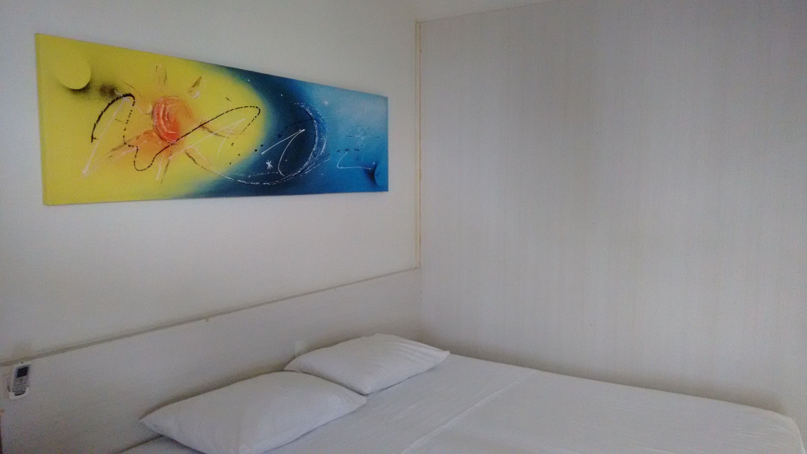 A single bed with white bedding in a room with a plain white wall.