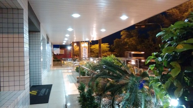 A hotel entrance with a tiled facade, outdoor seating area, and potted plants. - Atalaia Apart Hotel (Aracaju)