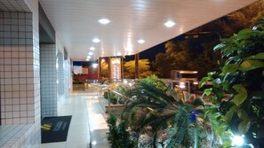 A hotel entrance with a tiled facade, outdoor seating area, and potted plants. - Atalaia Apart Hotel (Aracaju)