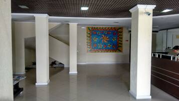 Un hall d’entrée spacieux avec un escalier, une fresque murale colorée et un comptoir d’accueil.