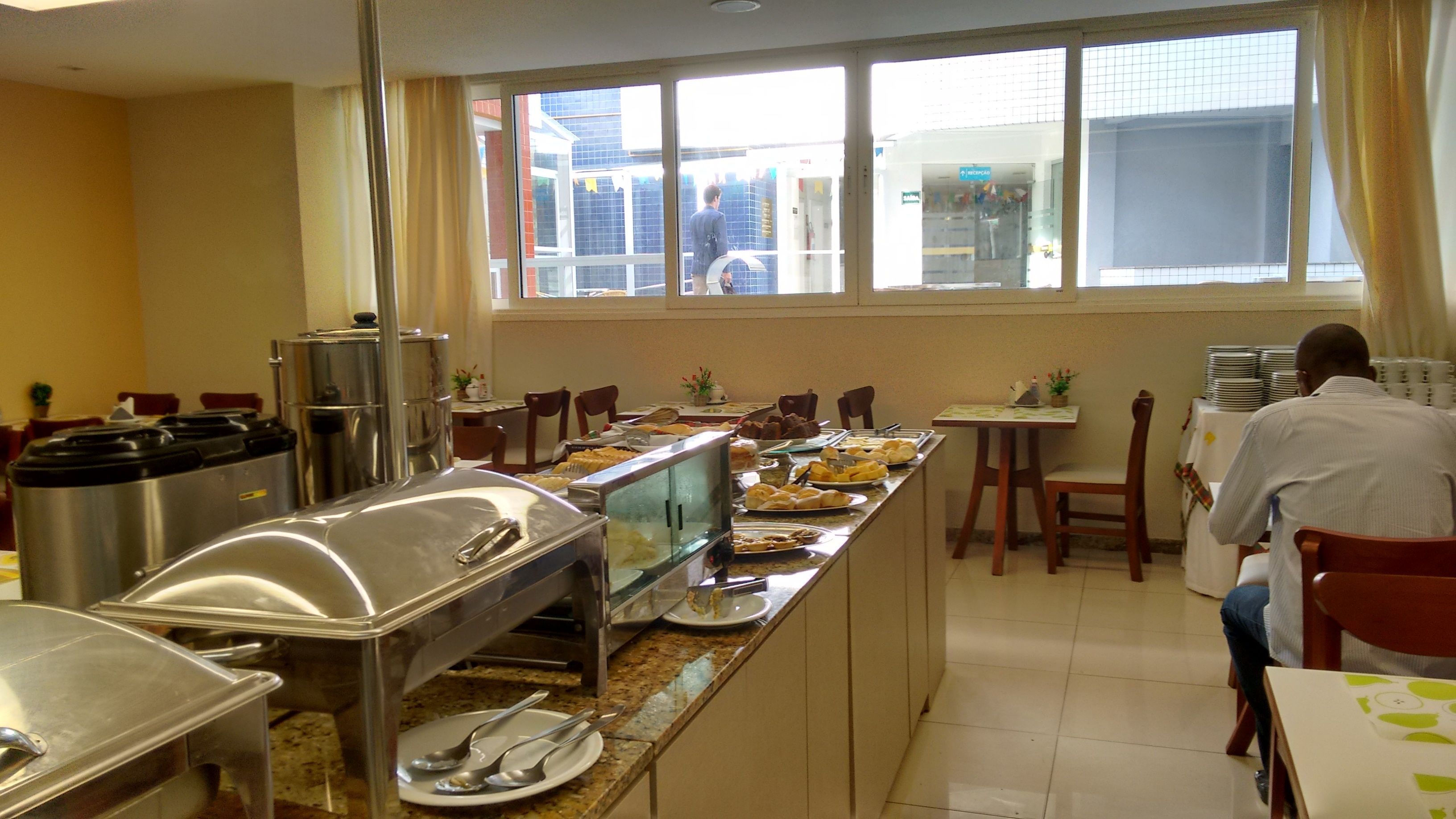 A buffet setup with various food items, a window view, and a person in the background.