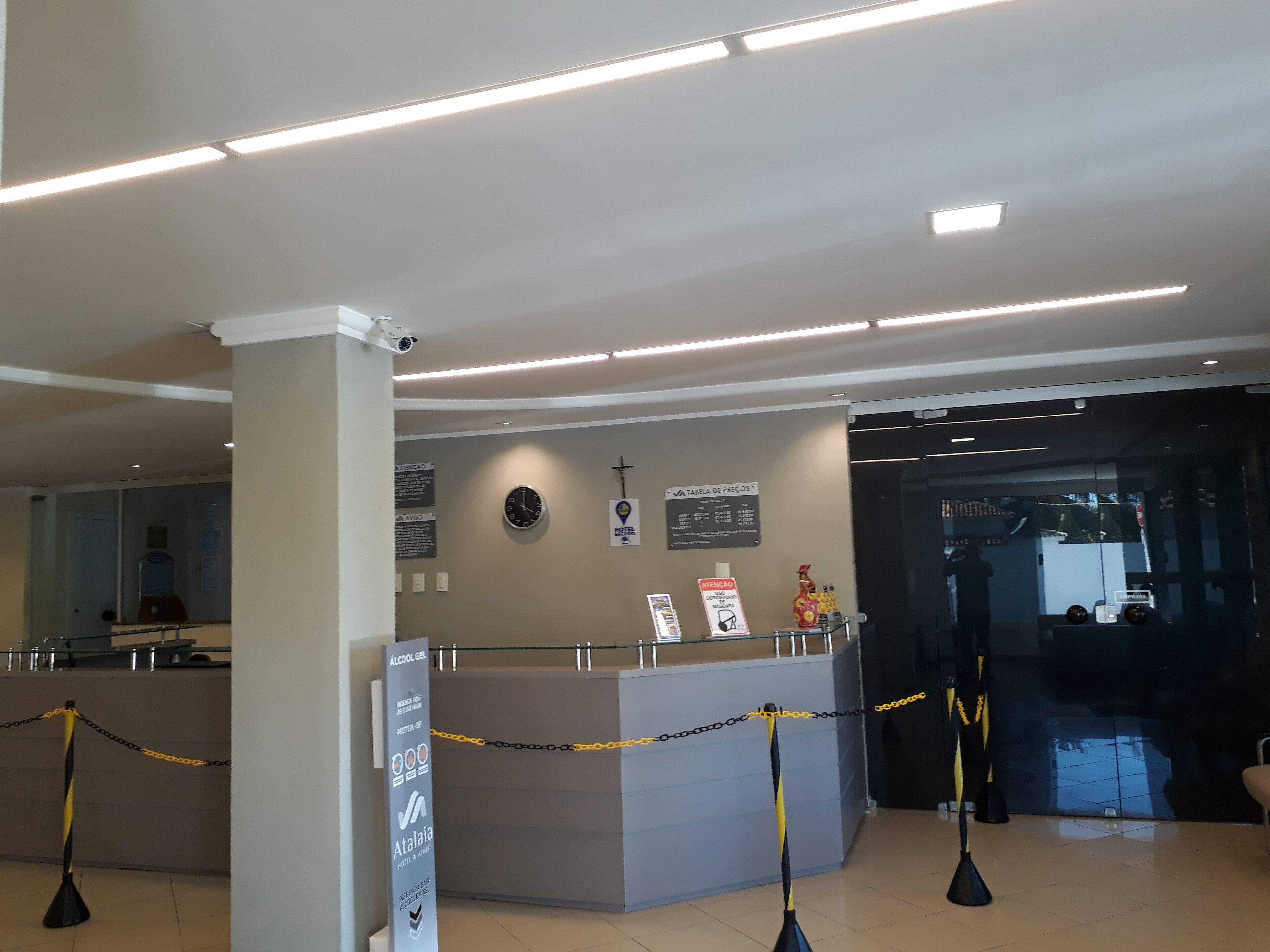 Un espace d’accueil d’hôtel comprenant un comptoir, une caméra de surveillance et des panneaux d’information.