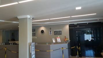 Un espace d’accueil d’hôtel comprenant un comptoir, une caméra de surveillance et des panneaux d’information.