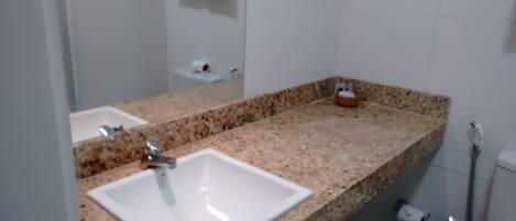 Un baño con un lavabo blanco, un espejo y una toalla colgada en la pared.