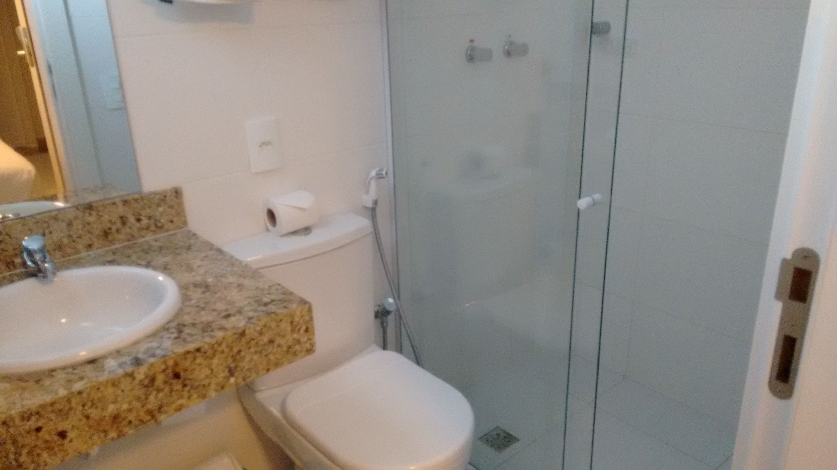 A bathroom with a sink, toilet, and glass shower enclosure.