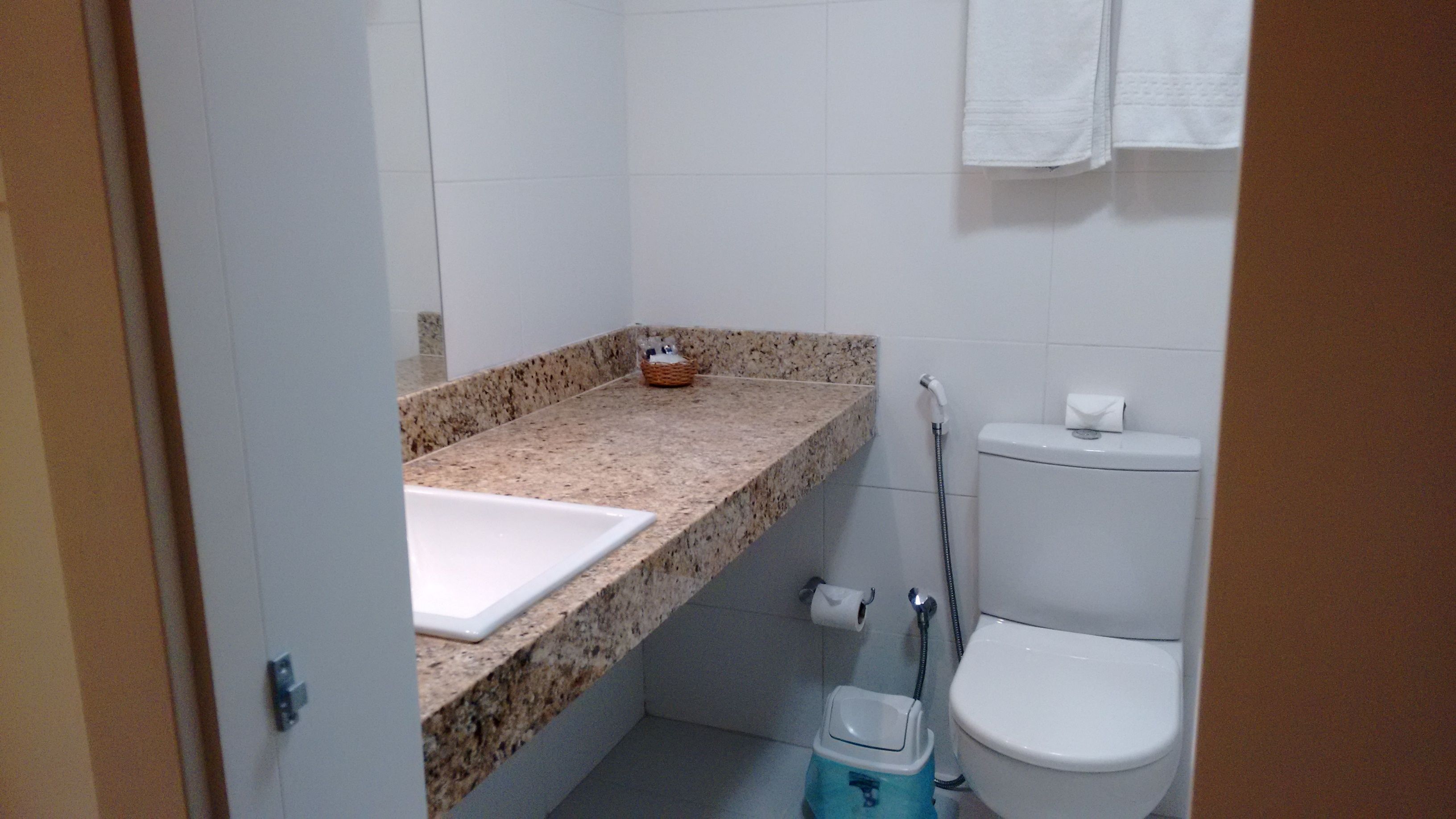 A small bathroom with a granite countertop, a toilet, and a shower.